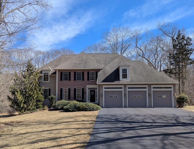 view of front facade with an attached garage, driveway, and a shingled roof