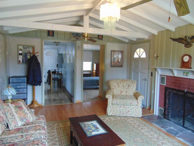 living area with visible vents, ceiling fan, lofted ceiling with beams, a fireplace, and wood finished floors