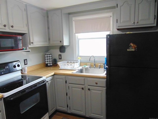 kitchen featuring light countertops, freestanding refrigerator, electric stove, and a sink