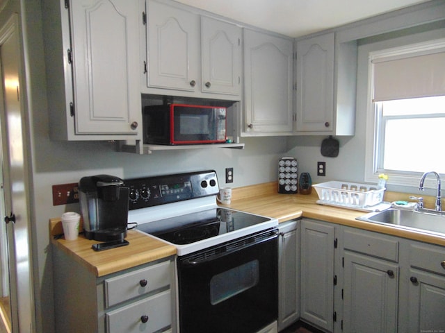 kitchen with light countertops, electric range, gray cabinets, and a sink