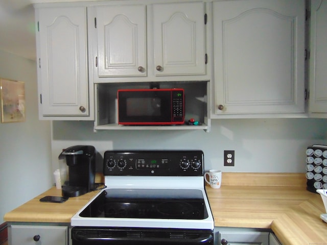 kitchen with white cabinetry, range with electric stovetop, and light countertops