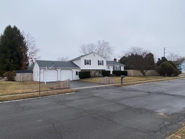 view of front of house featuring aphalt driveway, stone siding, an attached garage, and fence