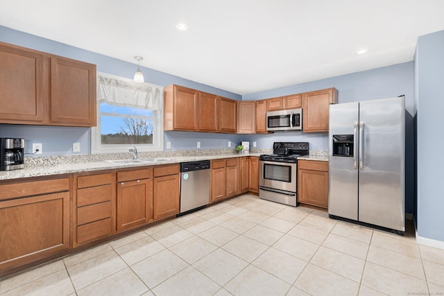 kitchen with a sink, brown cabinets, recessed lighting, light stone countertops, and stainless steel appliances