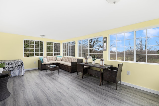sunroom with wood finished floors, a wooden deck, and baseboards