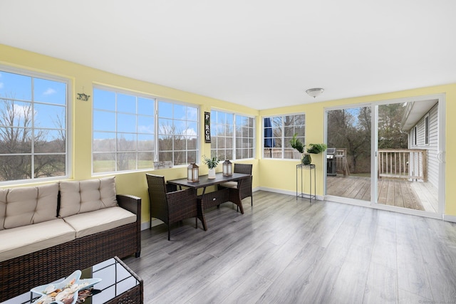 sunroom featuring a healthy amount of sunlight, a wooden deck, baseboards, and wood finished floors