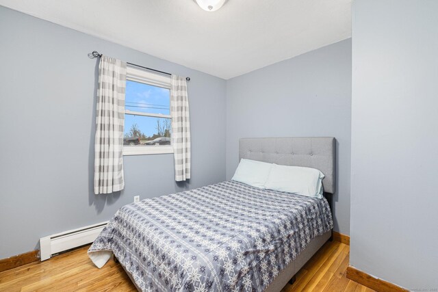 bedroom featuring a baseboard radiator, wood finished floors, and baseboards