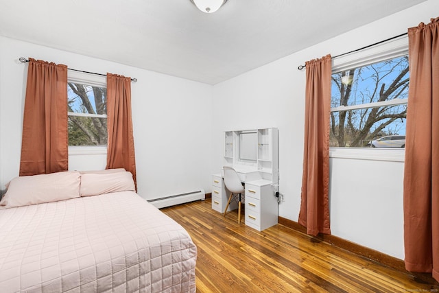 bedroom featuring light wood finished floors, a baseboard radiator, and baseboards