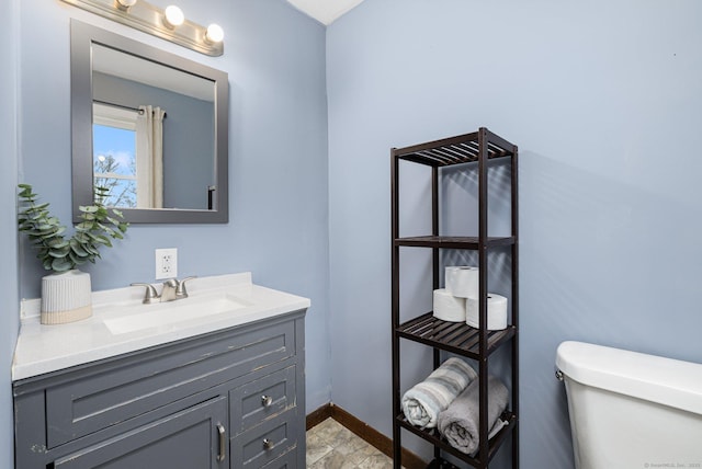half bath featuring vanity, baseboards, and toilet