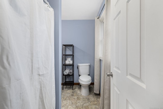 full bath featuring toilet and baseboards