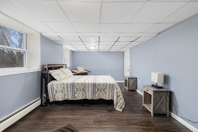 bedroom with baseboards, a drop ceiling, wood finished floors, and baseboard heating