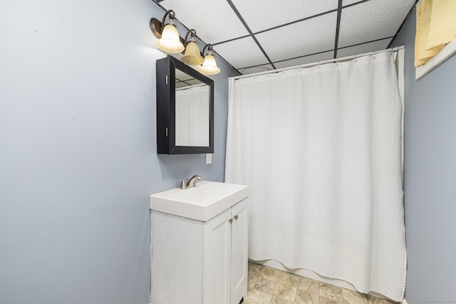 full bath featuring a paneled ceiling, vanity, a shower with curtain, and stone finish flooring