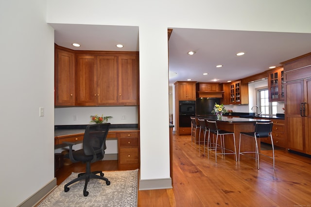 40 Shields Rd, Woodstock, CT 06281 - kitchen with dark countertops, a breakfast bar, light wood-type flooring, glass insert cabinets, and recessed lighting