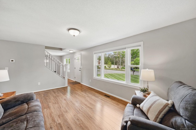 living room with baseboards, stairs, and wood finished floors