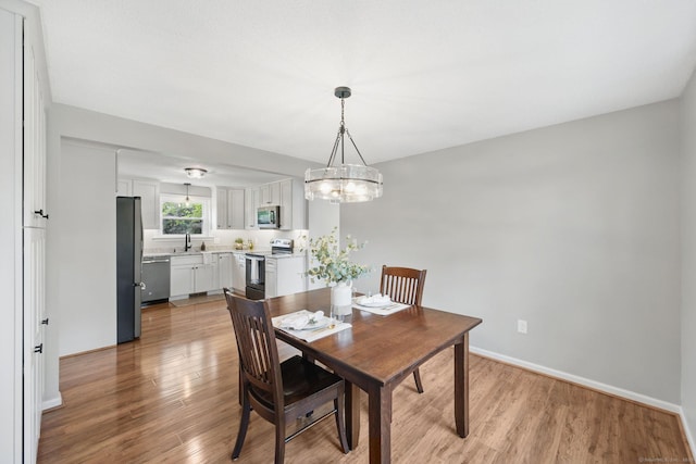 dining room featuring light wood-type flooring, baseboards, and a chandelier