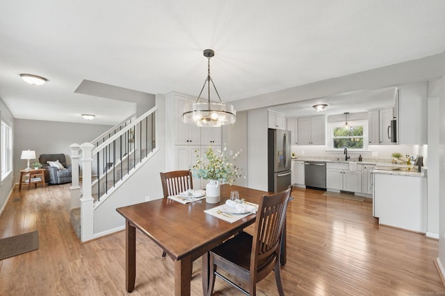 dining space featuring light wood-type flooring, stairway, a chandelier, and baseboards