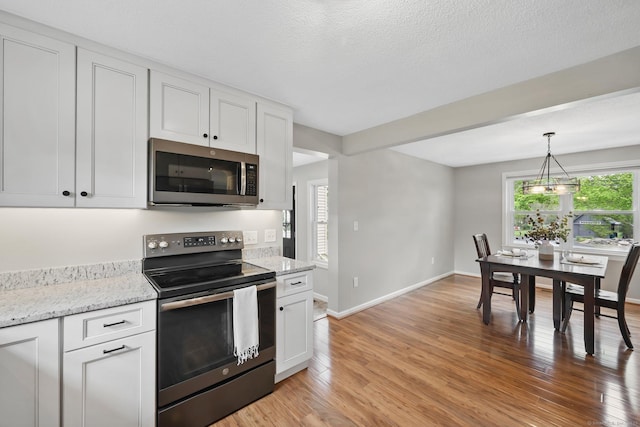kitchen with appliances with stainless steel finishes, light wood-style floors, white cabinets, and baseboards