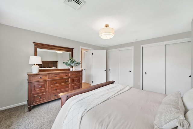bedroom with two closets, light colored carpet, and baseboards