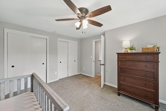 bedroom featuring multiple closets, light colored carpet, baseboards, and ceiling fan