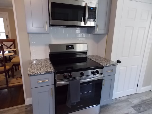 kitchen with light stone counters, gray cabinetry, wood finished floors, and stainless steel appliances