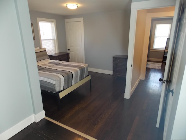 bedroom with dark wood-style floors and baseboards