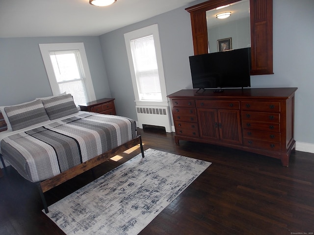 bedroom with dark wood finished floors, multiple windows, radiator, and baseboards