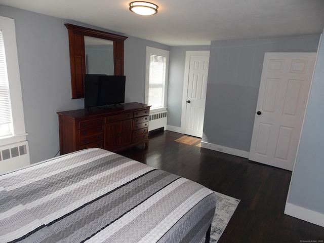 bedroom with baseboards, dark wood-style floors, and radiator heating unit