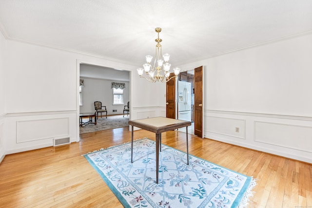 32 Woodmont Rd, Avon, CT 06001 - dining space with a chandelier, light wood-style flooring, crown molding, a wainscoted wall, and a decorative wall