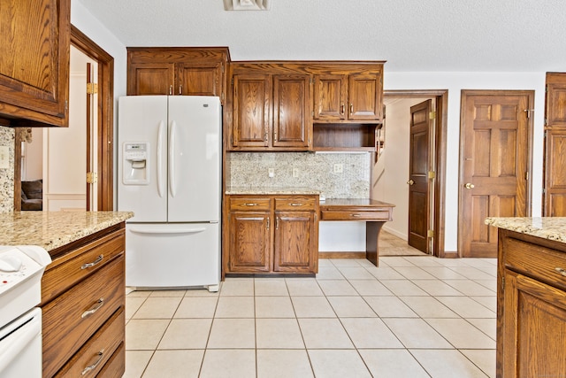 32 Woodmont Rd, Avon, CT 06001 - kitchen with white fridge with ice dispenser, tasteful backsplash, brown cabinetry, light tile patterned floors, and light stone countertops