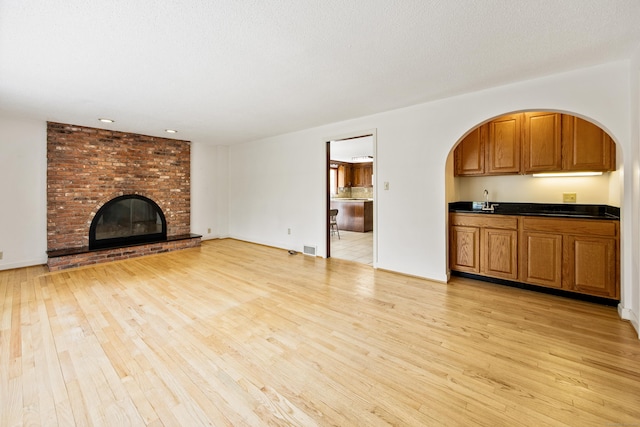 32 Woodmont Rd, Avon, CT 06001 - unfurnished living room with light wood-style floors, a brick fireplace, and arched walkways