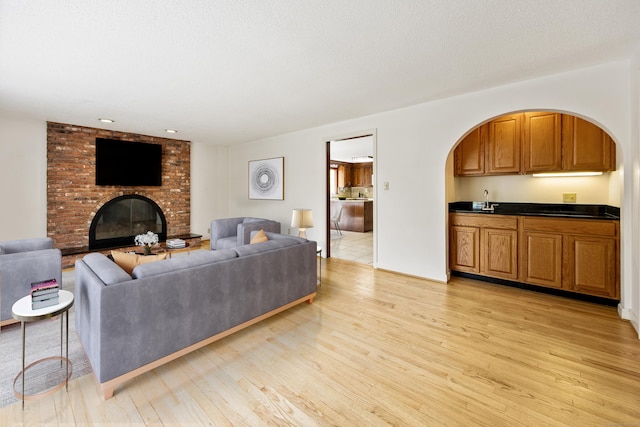 32 Woodmont Rd, Avon, CT 06001 - living area with light wood-type flooring, a brick fireplace, arched walkways, and wet bar