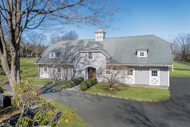 view of front of home featuring a front lawn and a shingled roof