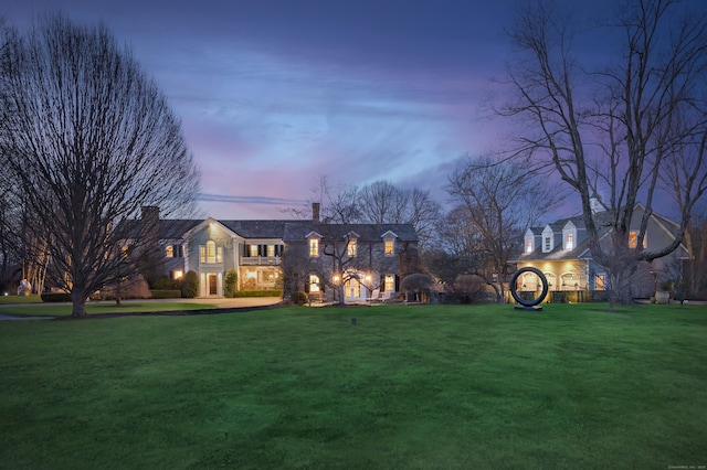 view of front of property with stone siding, a front lawn, and a chimney