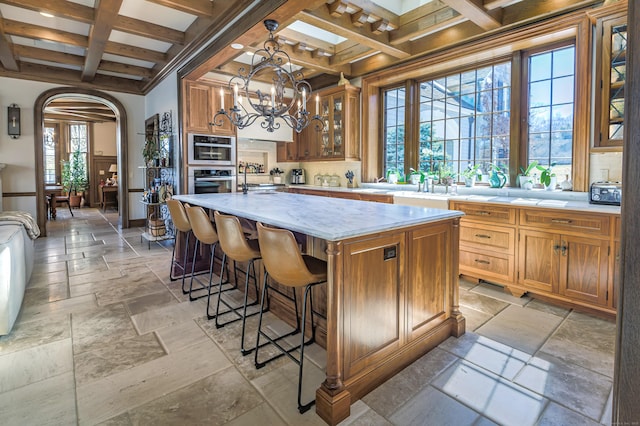 kitchen with coffered ceiling, stone tile flooring, beamed ceiling, light countertops, and oven