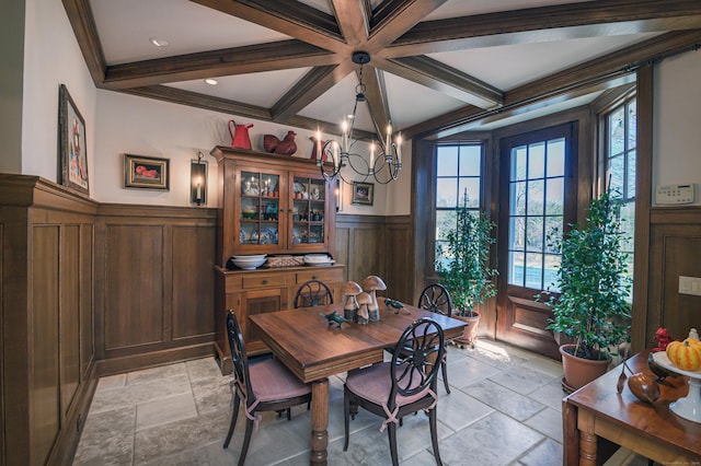 dining room featuring coffered ceiling, stone tile flooring, a wealth of natural light, wainscoting, and beamed ceiling