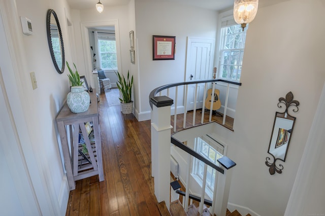 hall featuring hardwood / wood-style flooring, baseboards, and an upstairs landing