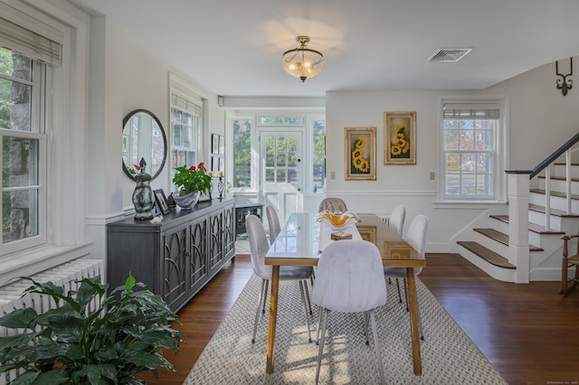 dining room with radiator, visible vents, stairway, dark wood-style floors, and wainscoting