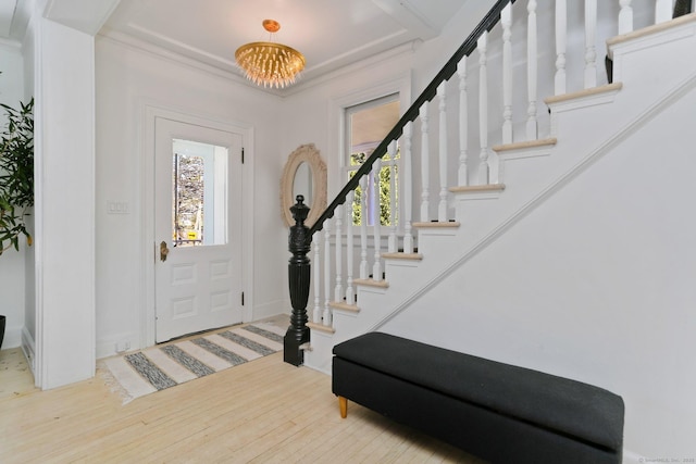 foyer entrance with a notable chandelier, stairway, and wood finished floors