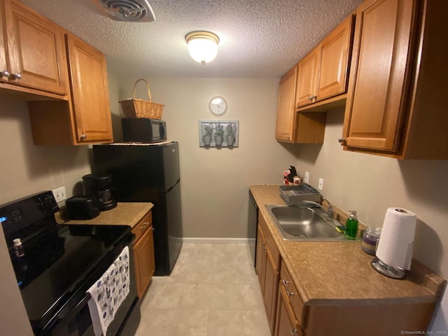 kitchen featuring visible vents, black appliances, a sink, a textured ceiling, and baseboards