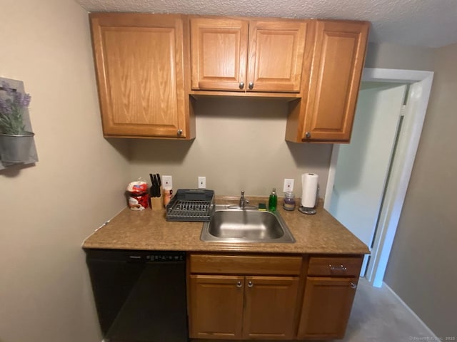 kitchen featuring a textured ceiling, black dishwasher, and a sink