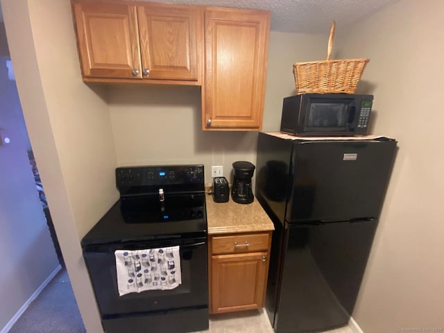 kitchen with a textured ceiling, black appliances, and baseboards