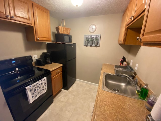 kitchen with black appliances, a sink, a textured ceiling, light countertops, and baseboards