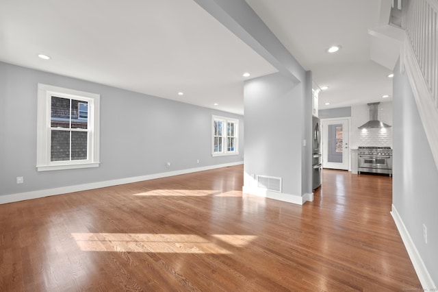 unfurnished living room featuring wood finished floors, baseboards, visible vents, and recessed lighting