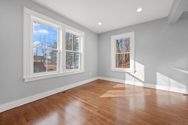 unfurnished room with wood finished floors, recessed lighting, baseboards, and visible vents