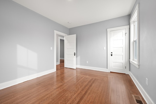 unfurnished bedroom featuring wood finished floors, baseboards, and visible vents