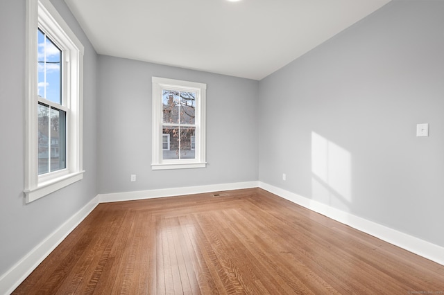 unfurnished room with baseboards and wood-type flooring