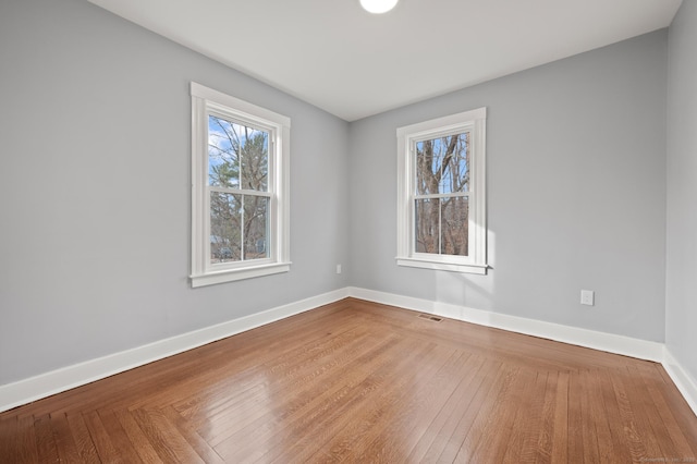 unfurnished room featuring wood finished floors, visible vents, and baseboards