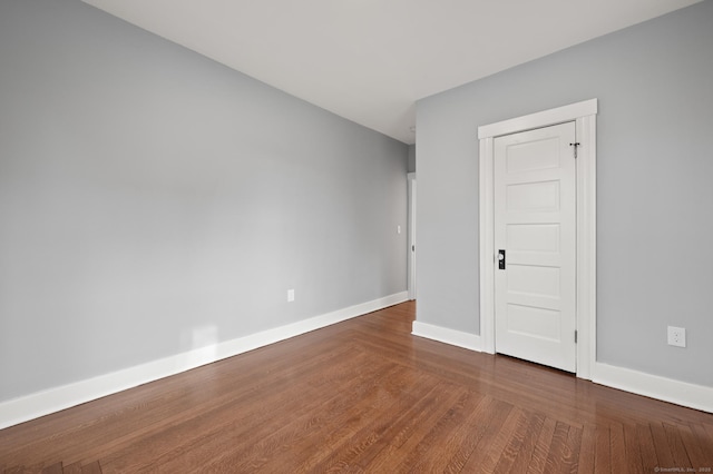spare room with baseboards and wood finished floors
