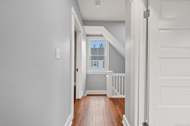 corridor with an upstairs landing, baseboards, and hardwood / wood-style flooring