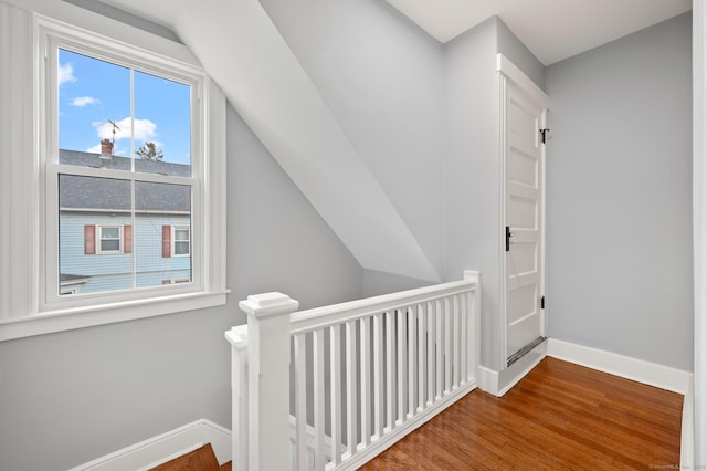 interior space with an upstairs landing, baseboards, lofted ceiling, and wood finished floors