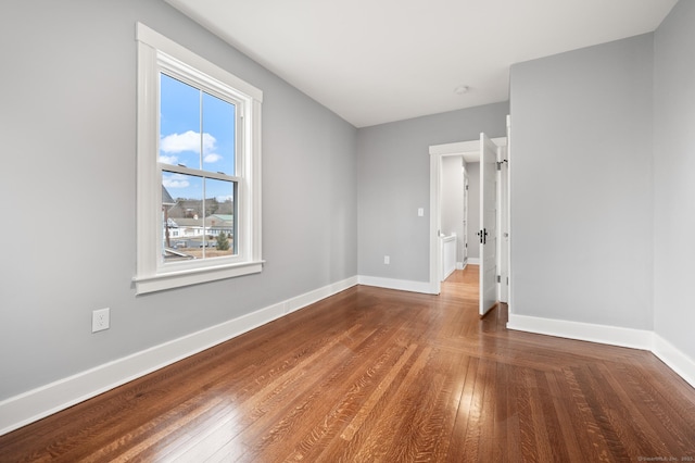 empty room featuring baseboards and hardwood / wood-style flooring